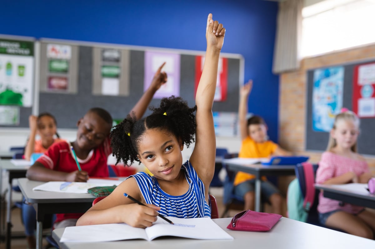 A young student raising her hand in class